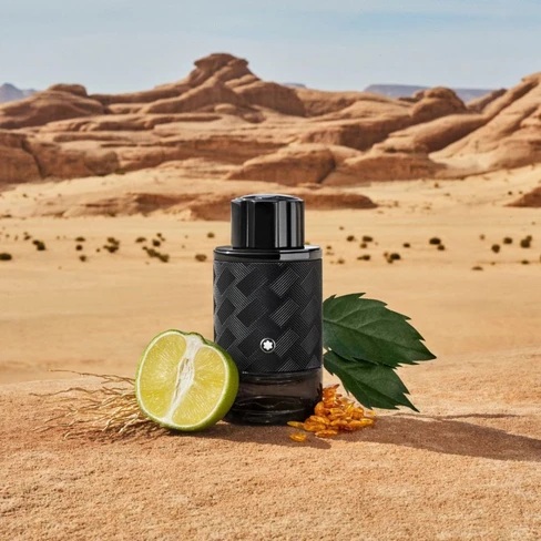 بطری عطر مون بلان اکسپلورر اکستریم با برگ سبز و برش لیمو در پسزمینه بیابانی